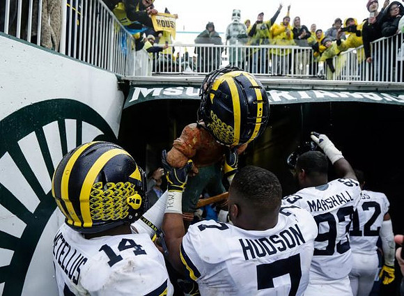 Josh Metellus (14), Lawrence Marshall (93), and Paul Bunyan Trophy