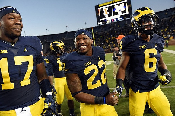 Tyrone Wheatley Jr. (17), Karan Higdon (22), and Kareem Walker (6)