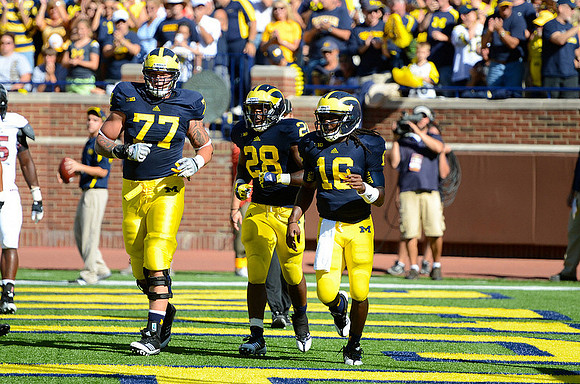 Taylor Lewan (77), Fitzgerald Toussaint (28), and Denard Robinson (16)