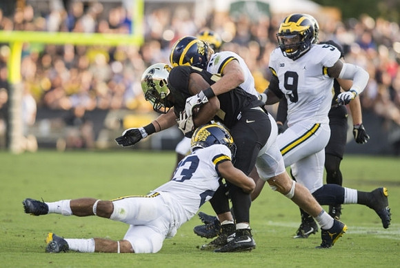 Chase Winovich (15), Tyree Kinnel (23), and Mike McCray (9)