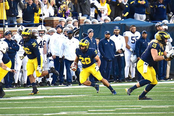 J'Marick Woods (26), Brandon Watson (28), and Chase Winovich (15)