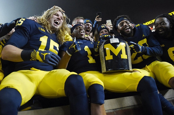 Chase Winovich (15), Ambry Thomas (1), Brandon Watson (28), Kareem Walker (6), and The Little Brown Jug