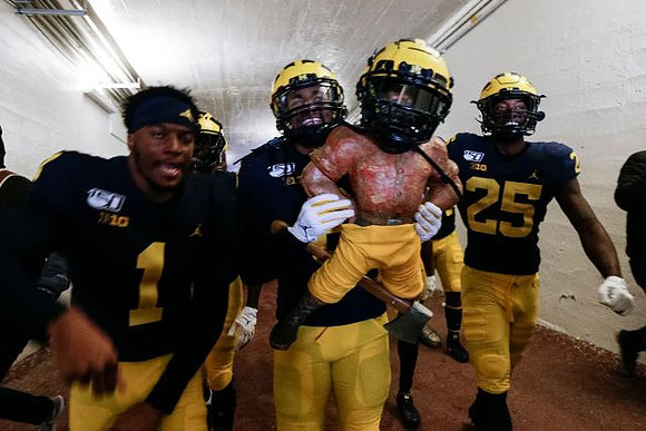 Ambry Thomas (1), Devin Gil (8), Paul Bunyan Trophy, and Hassan Haskins (25)