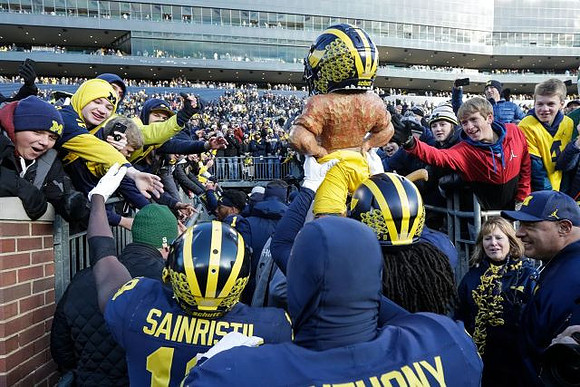 Mike Sainristil (19), Jordan Anthony (34), Devin Gil (8), and Paul Bunyan Trophy