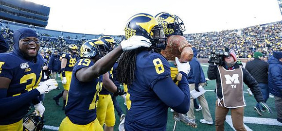 Jordan Anthony (34), Mike Sainristil (19), Devin Gil (8), and Paul Bunyan Trophy