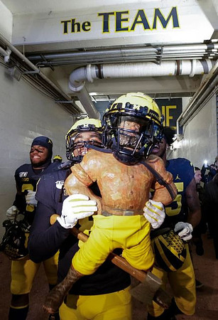 Jordan Anthony (34), Devin Gil (8), Paul Bunyan Trophy, and Hassan Haskins (25)