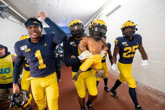 Ambry Thomas (1), Devin Gil (8), Paul Bunyan Trophy, and Hassan Haskins (25)