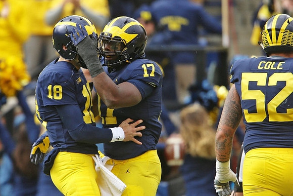 Brandon Peters (18), Tyrone Wheatley Jr. (17), and Mason Cole (52)