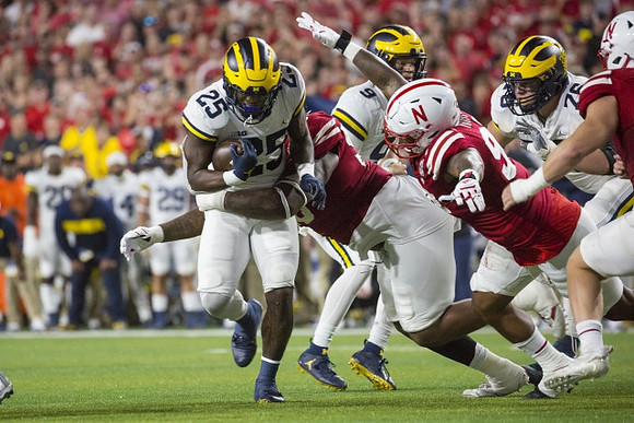 Hassan Haskins (25), J.J. McCarthy (9), and Ryan Hayes (76)