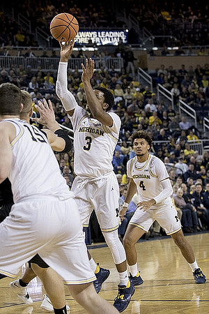 Jon Teske (15), Zavier Simpson (3), and Isaiah Livers (4)
