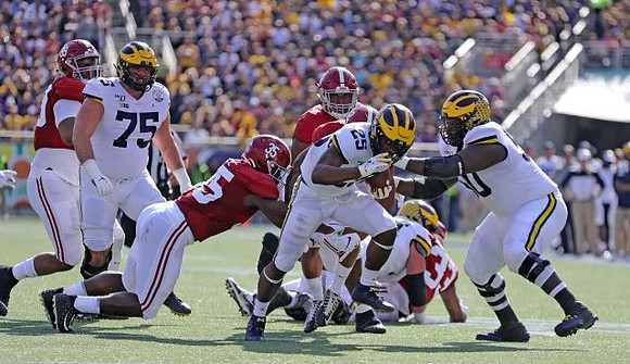 Jon Runyan Jr. (75), Hassan Haskins (25), and Michael Onwenu (50)