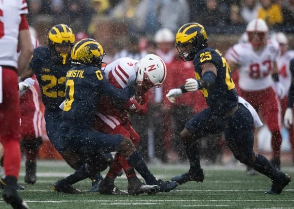 Michael Barrett (23), Mike Sainristil (0), and Junior Colson (25)