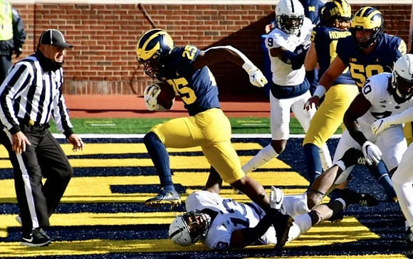 Hassan Haskins (25), Joel Honigford (85), and Zach Carpenter (58)