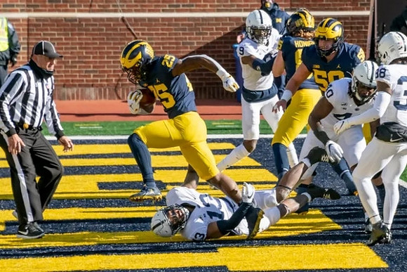 Hassan Haskins (25), Joel Honigford (85), and Zach Carpenter (58)