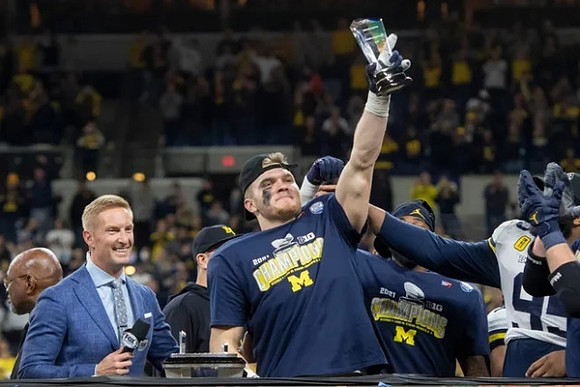 Aidan Hutchinson (97) and Big Ten Conference Championship Trophy