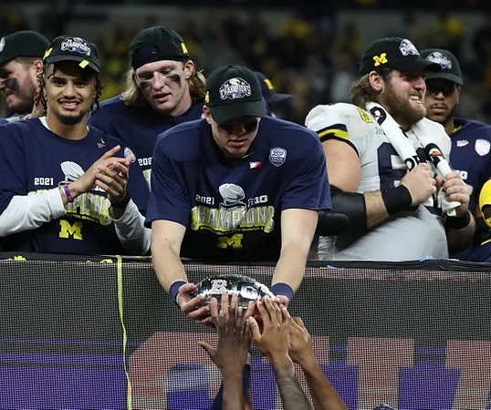 Ronnie Bell (8), Cade McNamara (12), Andrew Vastardis (68), and Big Ten Conference Championship Trophy