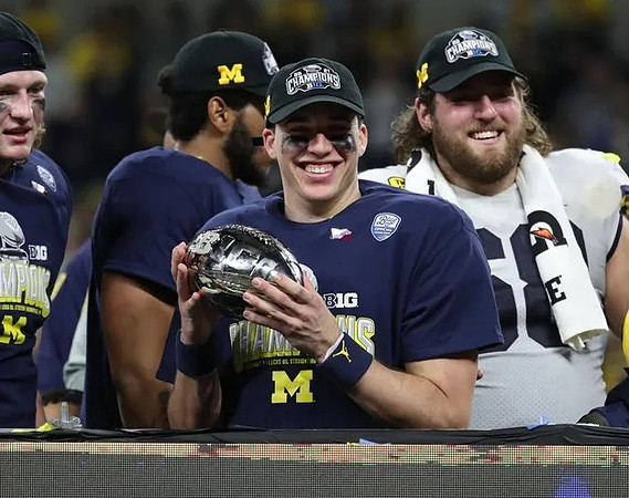 Cade McNamara (12), Andrew Vastardis (68), and Big Ten Conference Championship Trophy