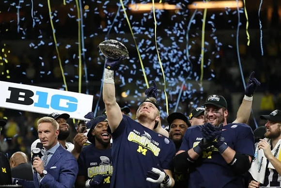 Aidan Hutchinson (97) and Big Ten Conference Championship Trophy
