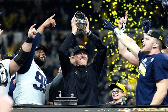 Donovan Jeter (95), Jim Harbaugh, Aidan Hutchinson (97), and Big Ten Conference Championship Trophy