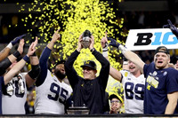 Andrew Vastardis (68), Donovan Jeter (95), Jim Harbaugh, Carter Selzer (89), Aidan Hutchinson (97), and Big Ten Conference Championship Trophy