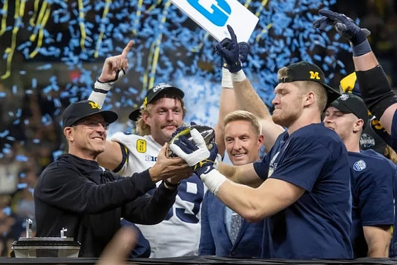 Jim Harbaugh, Carter Selzer (89), Aidan Hutchinson (97), and Big Ten Conference Championship Trophy