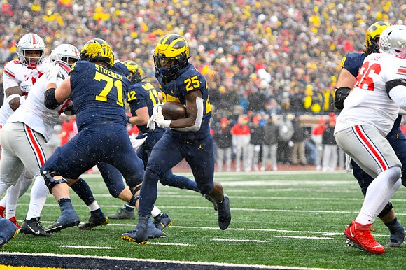 Andrew Stueber (71), Cade McNamara (12), and Hassan Haskins (25)