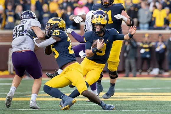 Hassan Haskins (25), J.J. McCarthy (9), and Andrew Stueber (71)