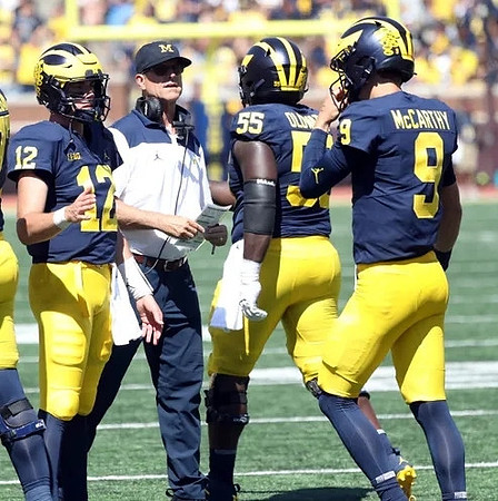 Cade McNamara (12), Jim Harbaugh, Olusegun Oluwatimi (55), and J.J. McCarthy (9)