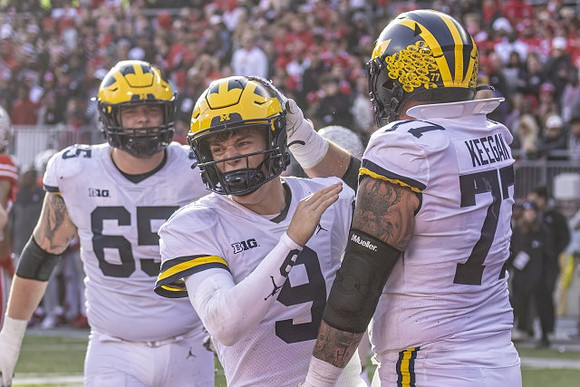 Zak Zinter (65), J.J. McCarthy (9), and Trevor Keegan (77)