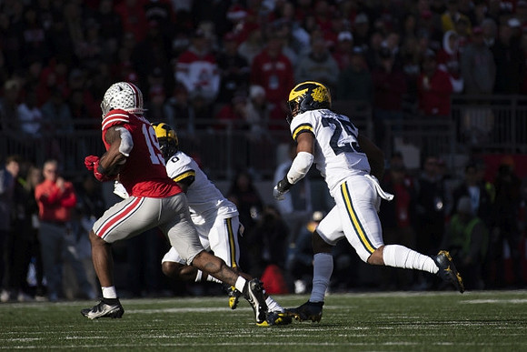 Mike Sainristil (0) and Junior Colson (25)