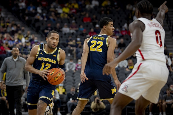 Juwan Howard, DeVante' Jones (12), and Caleb Houstan (22)