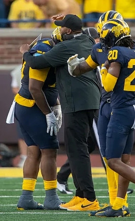 Kenneth Grant (78), Sherrone Moore, and Jyaire Hill (20)