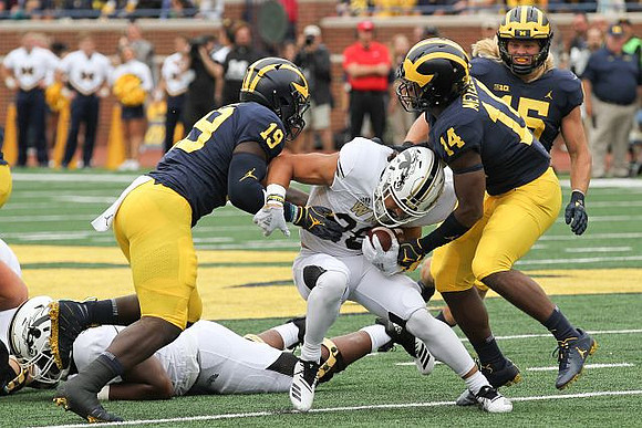 Kwity Paye (19), Josh Metellus (14), and Chase Winovich (15)