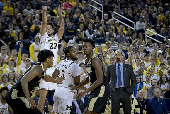 Brandon Johns Jr. (23), Zavier Simpson (3), and Juwan Howard