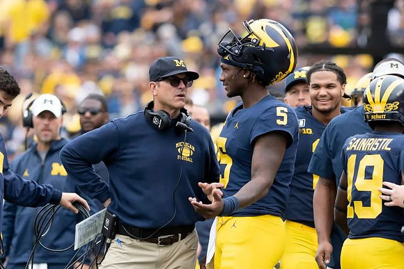 Jim Harbaugh, Joe Milton (5), Carlo Kemp (2), and Mike Sainristil (19)