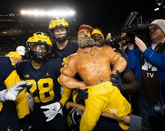 Quinten Johnson (28), Luke Schoonmaker (86), Paul Bunyan Trophy, and Mike Sainristil (0)