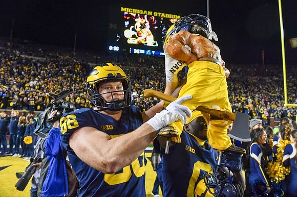 Luke Schoonmaker (86), Paul Bunyan Trophy, and Mike Sainristil (0)