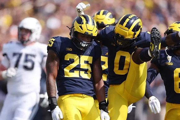 Junior Colson (25) and Mike Sainristil (0)