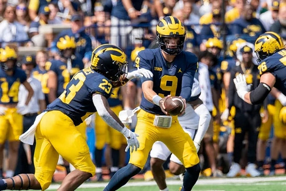 CJ Stokes (23), J.J. McCarthy (9), and Ryan Hayes (76)
