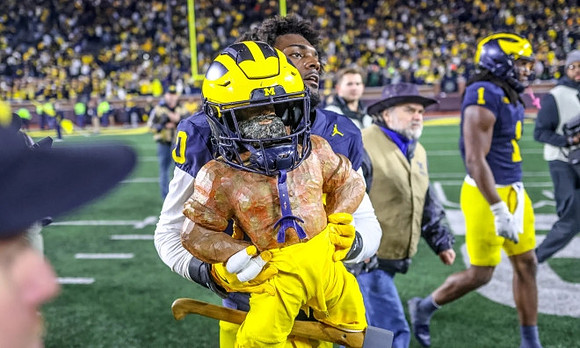 Josaiah Stewart (0), Paul Bunyan Trophy, and Jaishawn Barham (1)