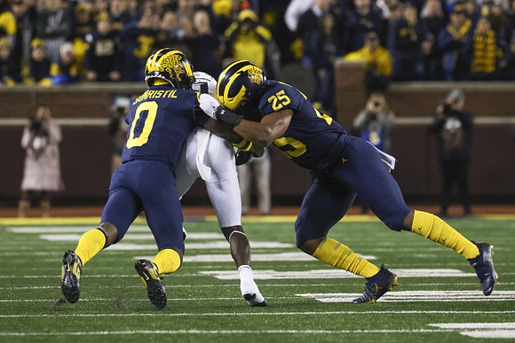 Mike Sainristil (0) and Junior Colson (25)