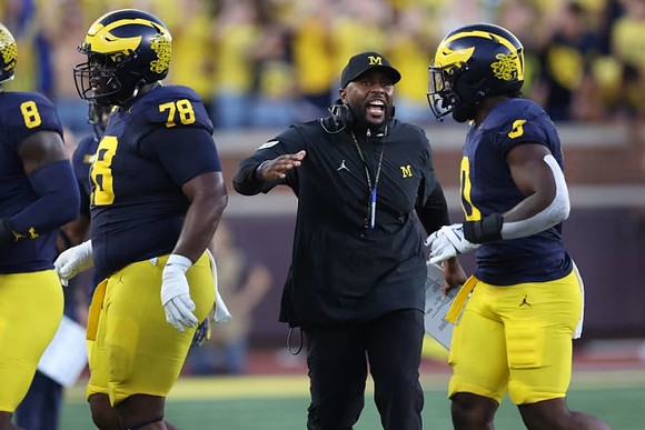 Tyler Morris (8), Myles Hinton (78), Sherrone Moore, and Semaj Morgan (0)